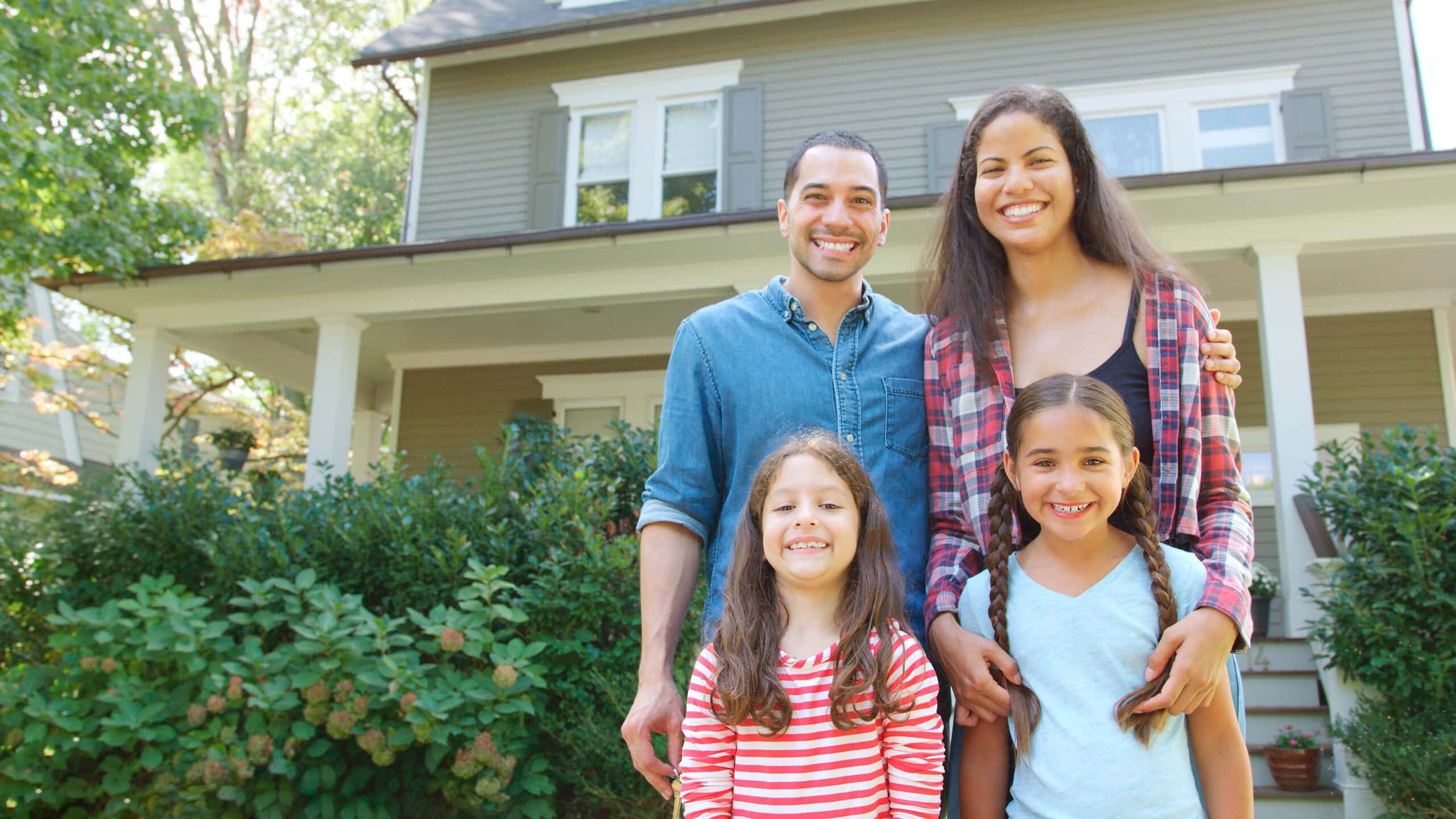 Portrait Of Smiling Family Standing In Front Of Their new Home